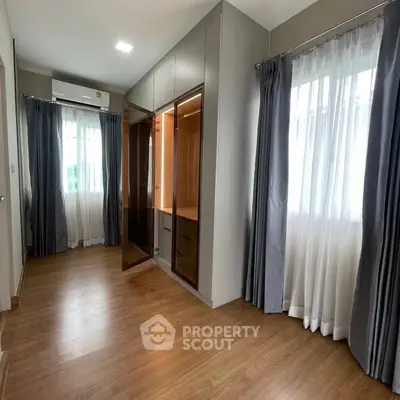 Spacious bedroom with wooden flooring and large windows for natural light