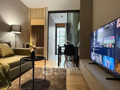 Modern living room with cozy seating and a view into a stylish bedroom, featuring contemporary decor and a flat-screen TV.