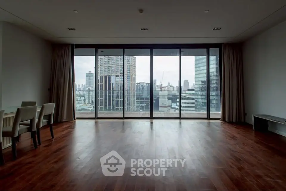 Spacious modern living room with floor-to-ceiling windows offering stunning city views.