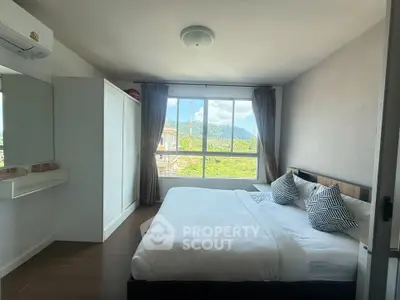 Spacious bedroom with large window offering scenic mountain views