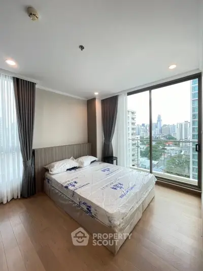 Modern bedroom with city view and large windows in high-rise apartment
