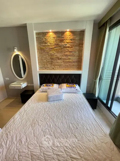 Modern bedroom with stylish brick accent wall and large window for natural light.