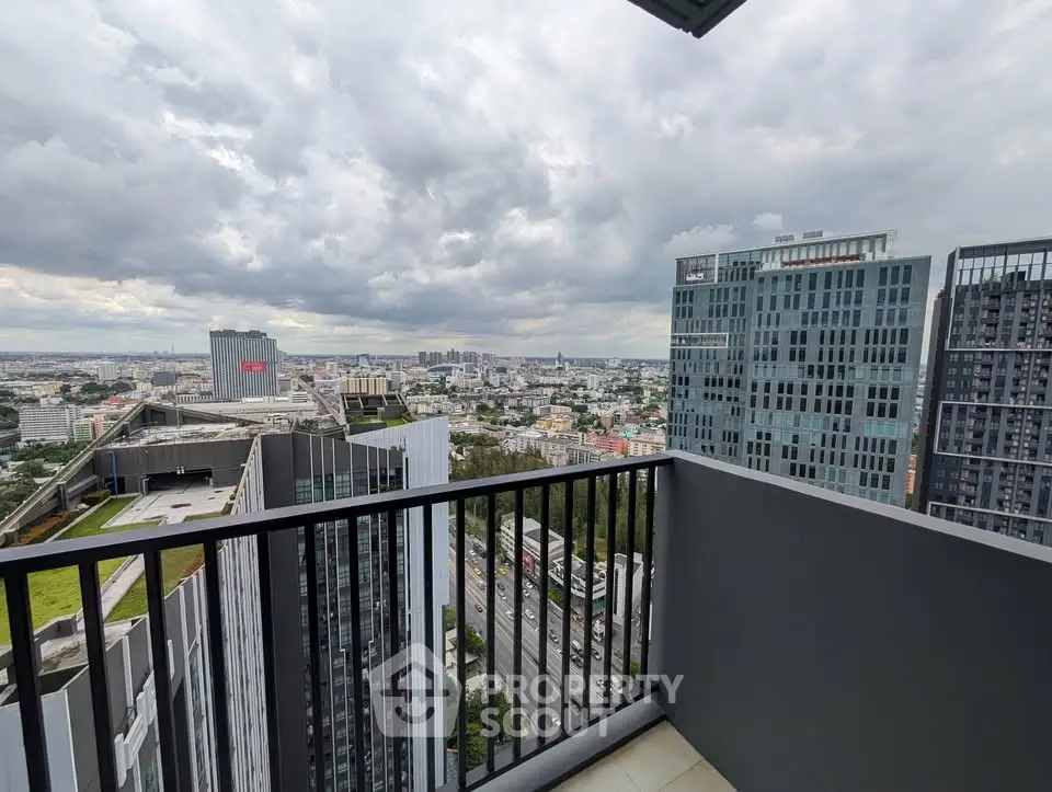 Stunning high-rise balcony view overlooking cityscape with modern skyscrapers and cloudy sky.