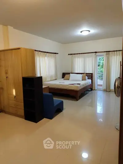 Spacious bedroom with large windows and modern furnishings in a serene setting.