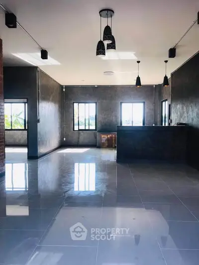 Spacious modern living room with sleek flooring and stylish lighting fixtures.