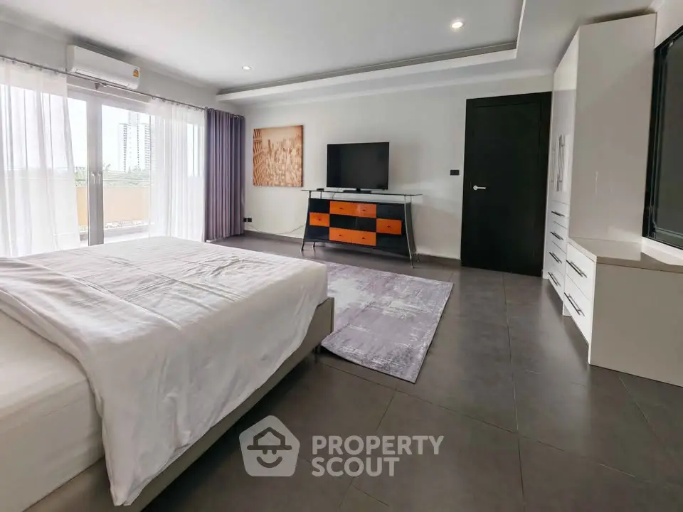 Spacious modern bedroom with large windows and stylish furniture in a luxury apartment.