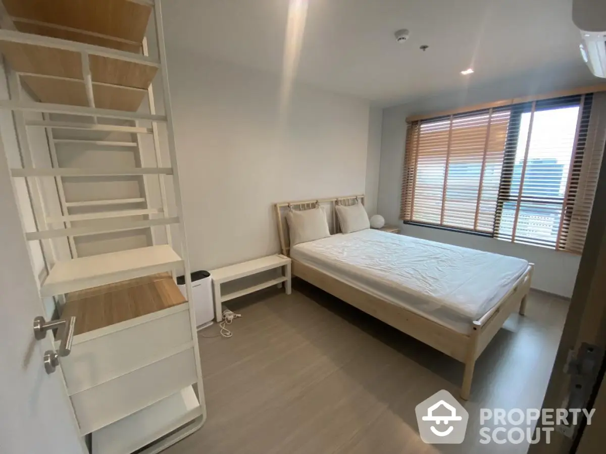 Modern minimalist bedroom with wooden bed frame and large window for natural light.