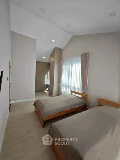 Spacious bedroom with twin beds and large windows in modern home
