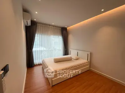 Modern minimalist bedroom with large window and wooden flooring