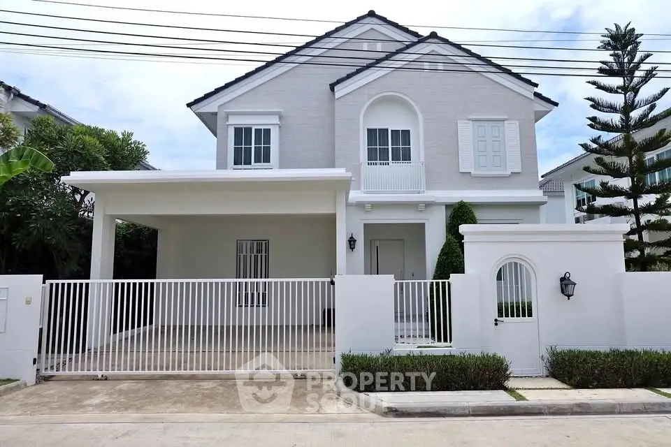 Elegant two-story house with gated driveway and manicured garden in a serene neighborhood.
