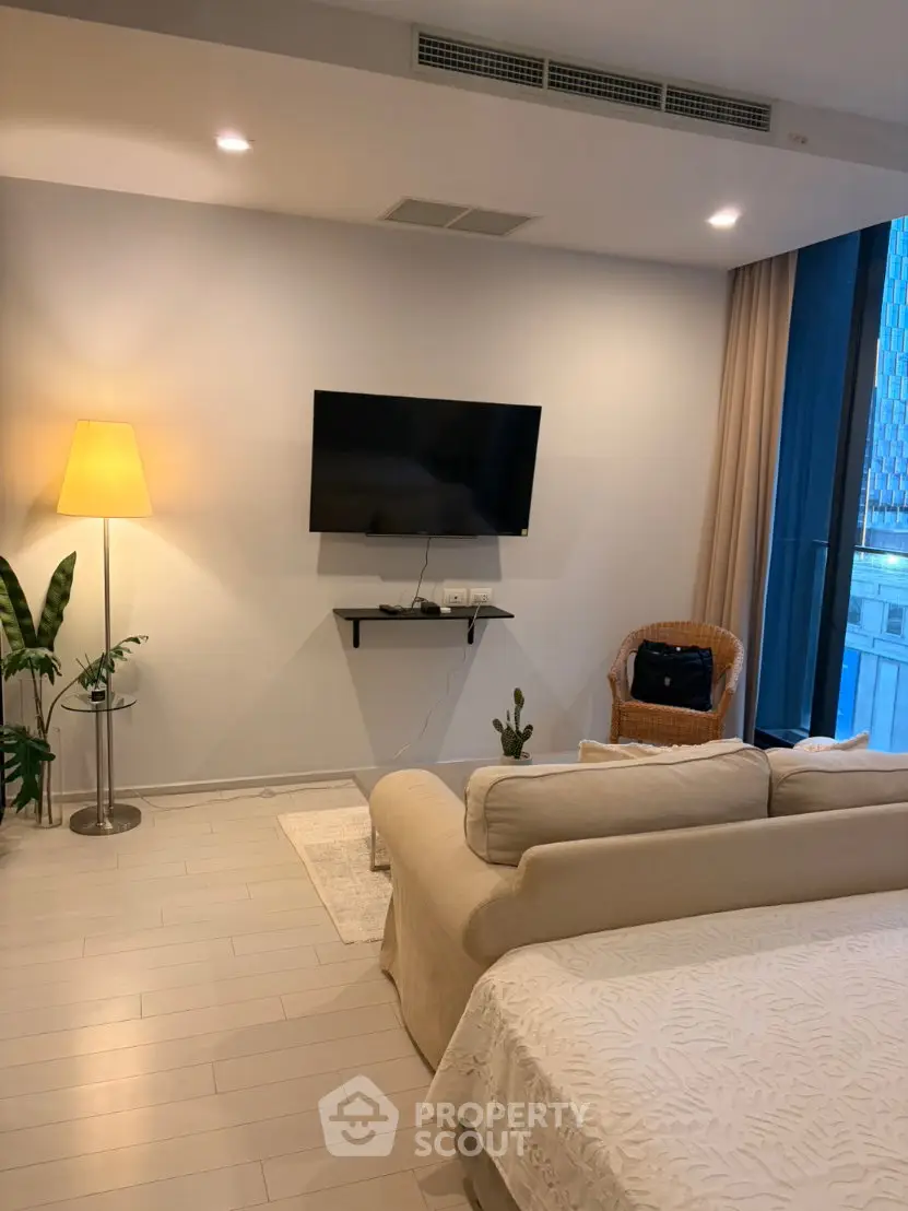 Modern living room with cozy sofa, wall-mounted TV, and elegant lighting in a stylish apartment.