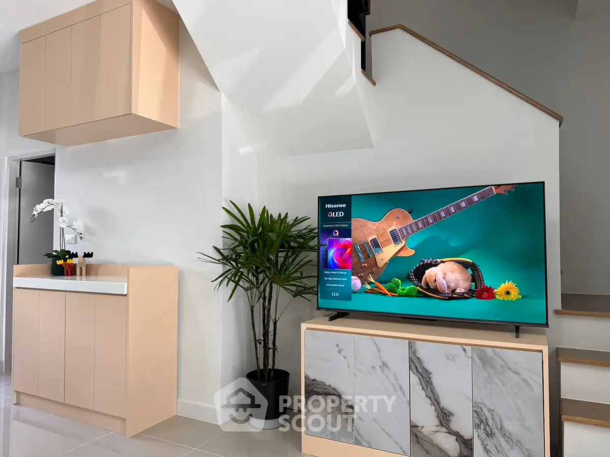 Modern living room with stylish TV setup and elegant cabinetry under staircase