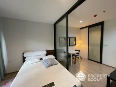 Modern bedroom with glass partition and study area, featuring sleek design and ample natural light.