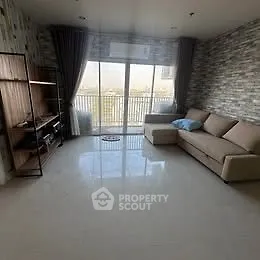 Spacious living room with modern decor and large windows leading to a balcony.