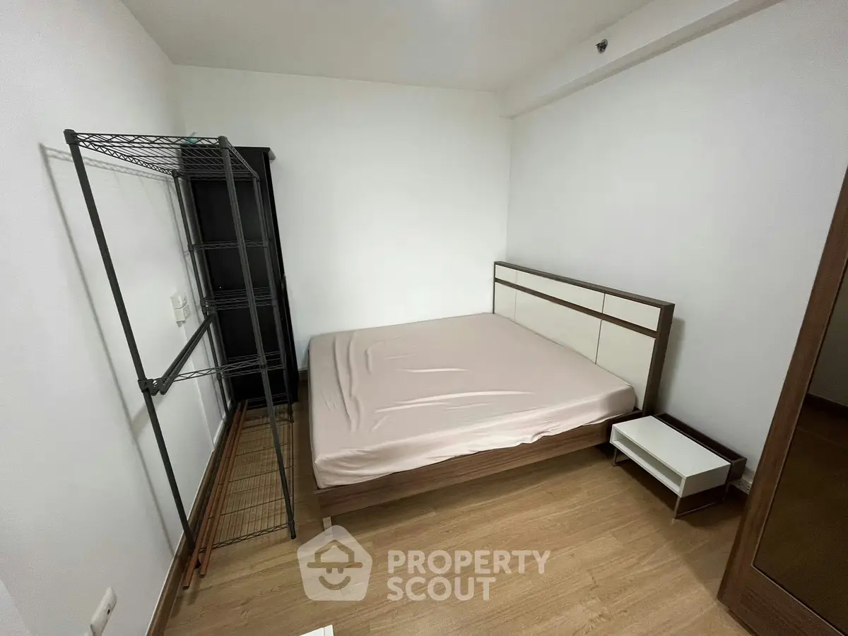 Cozy bedroom with minimalist design featuring a bed, nightstand, and open shelving unit.