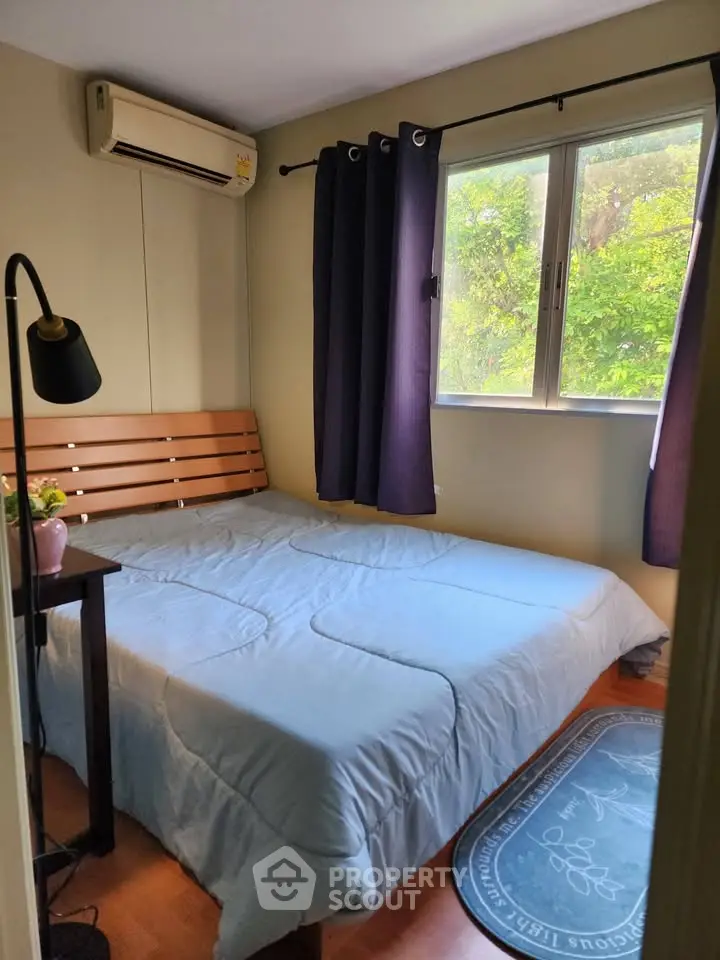 Cozy bedroom with large window and lush green view, featuring a comfortable bed and modern decor.