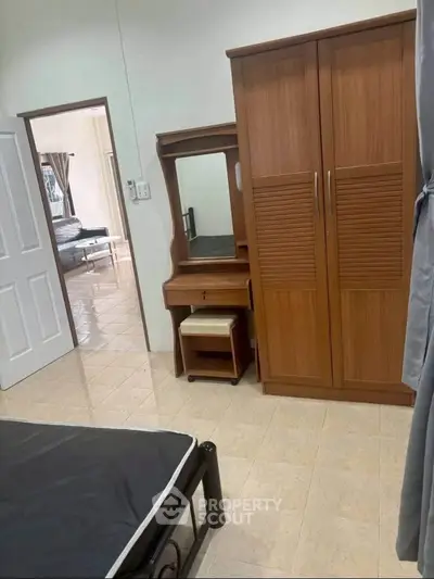 Spacious bedroom with wooden wardrobe and dressing table, offering a glimpse into an adjoining room.