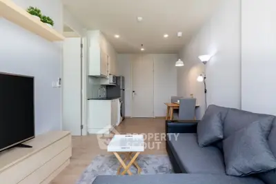 Modern living room with sleek furniture and open kitchen layout in a stylish apartment.