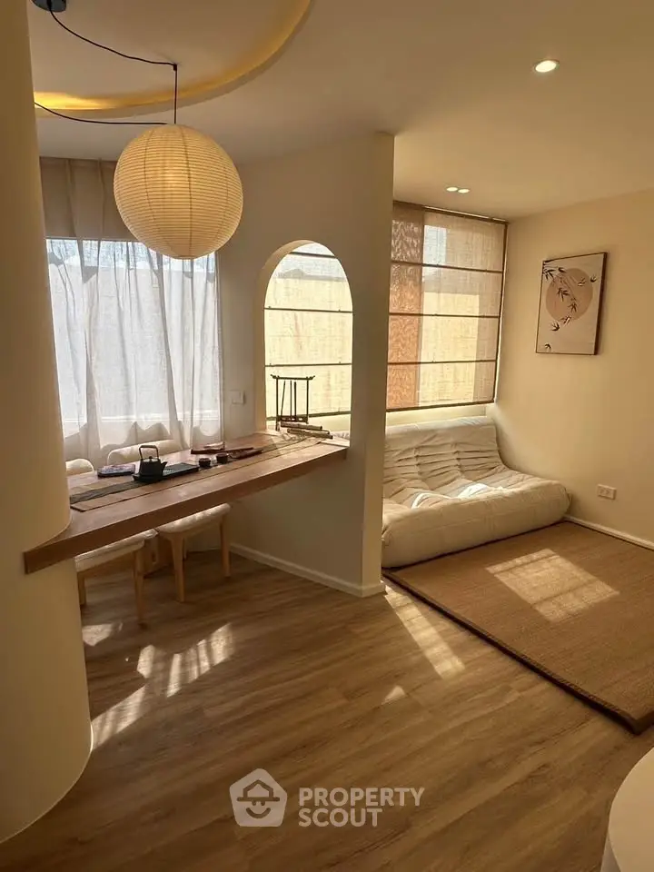 Cozy living room with natural light, wooden flooring, and minimalist decor for a serene ambiance.