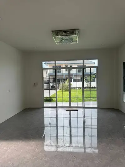Spacious living room with large windows offering garden view in modern home.