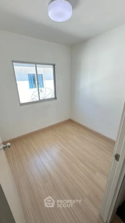 Bright empty room with wooden flooring and window, perfect for customization