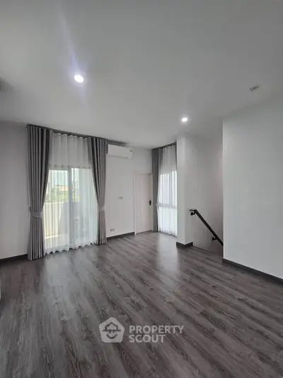 Spacious modern living room with elegant flooring and large windows for natural light.