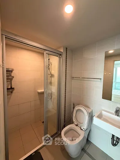 Modern bathroom with shower, toilet, and sink in a sleek tiled design.