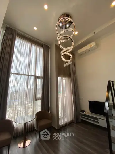 Luxurious high-ceiling living room with modern chandelier and large windows