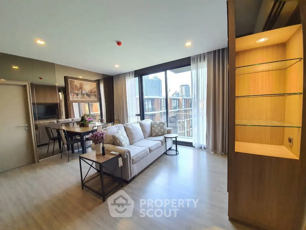 Spacious modern living room with large windows and elegant decor in a high-rise apartment.
