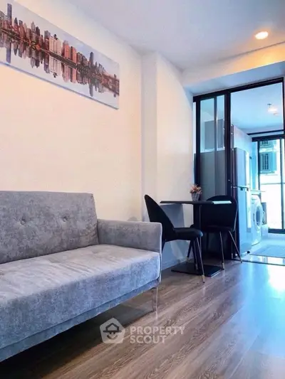 Modern living room with sleek sofa and dining area, featuring stylish decor and natural light.