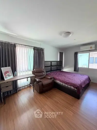 Spacious bedroom with modern furnishings and natural light, featuring a comfortable bed and stylish decor.