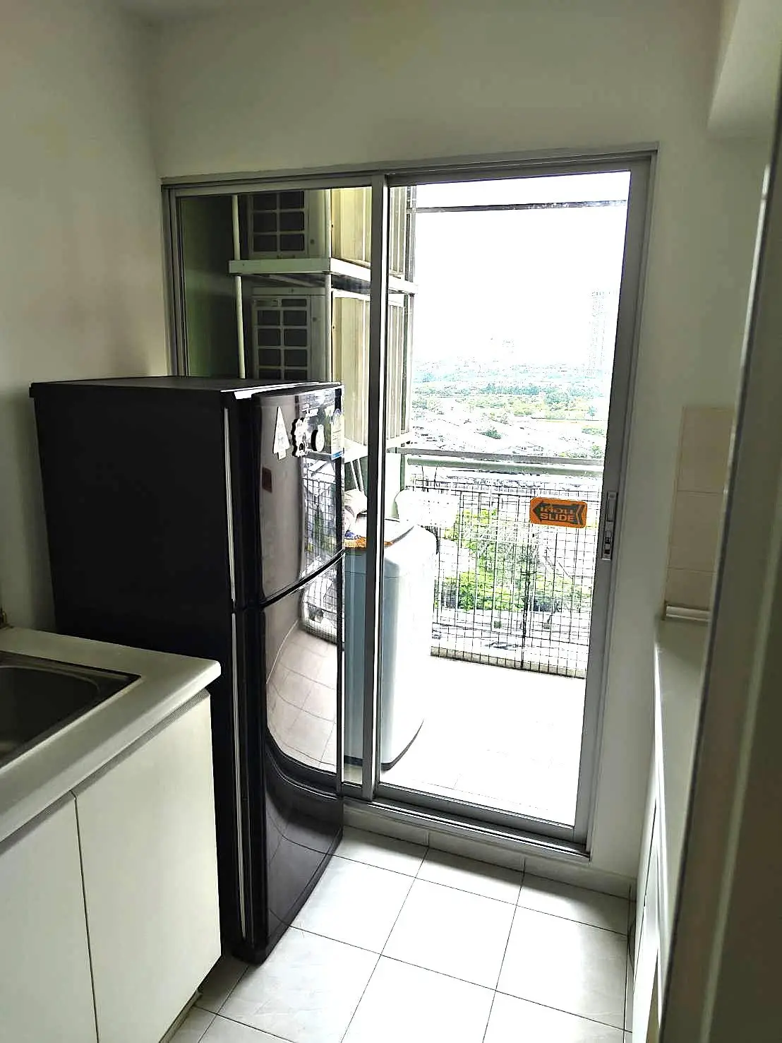 Compact kitchen with black fridge and balcony view in modern apartment