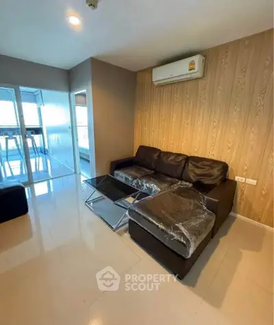 Modern living room with sleek black sofa and glass coffee table in stylish apartment.