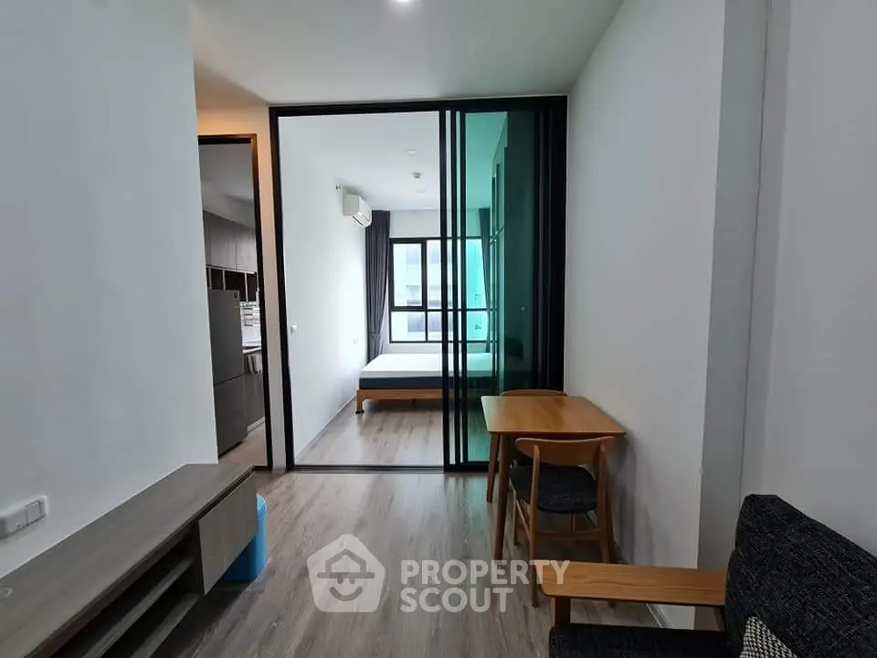 Modern apartment interior with open layout, featuring a cozy living area and a glimpse of the bedroom.