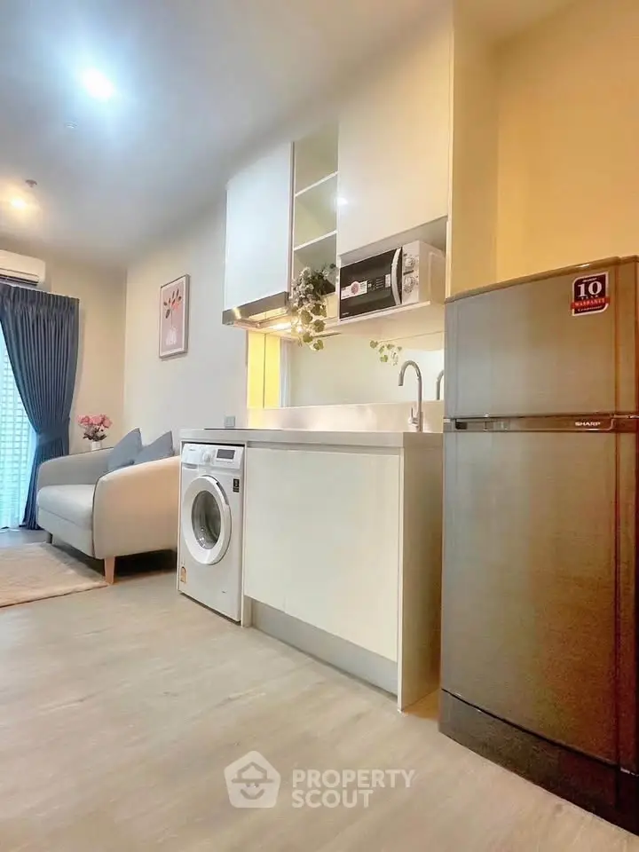 Modern apartment kitchen with washing machine and fridge, open layout, bright and inviting.
