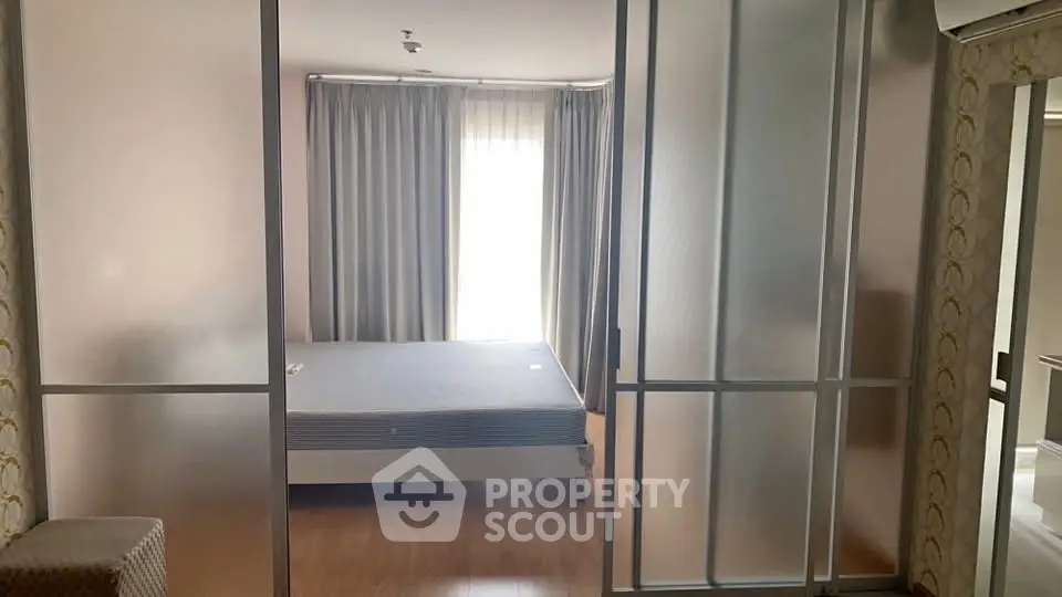 Spacious bedroom with frosted glass sliding doors and natural light.