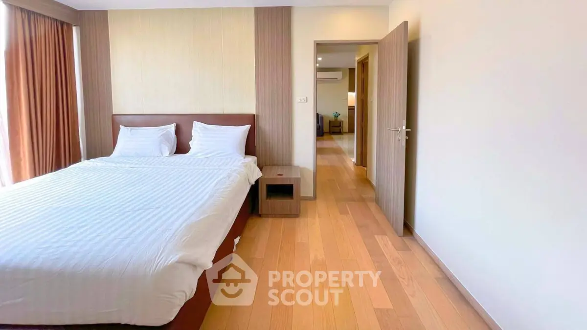 Spacious bedroom with wooden flooring and modern decor in a luxury apartment.