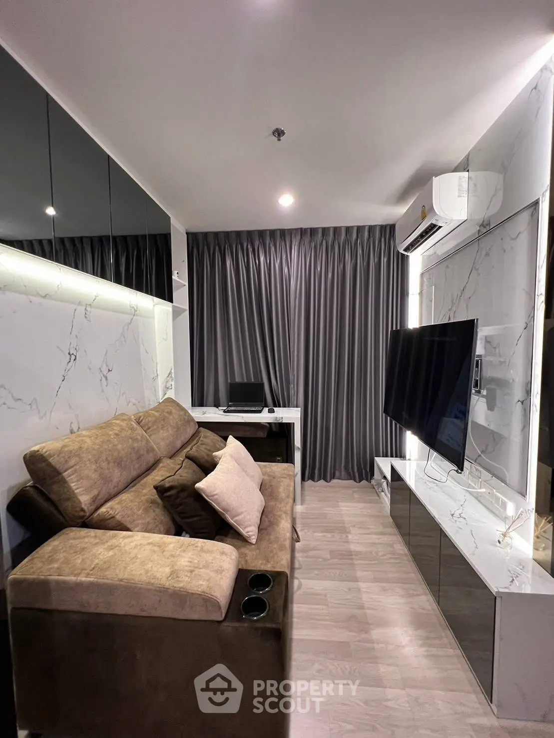Modern living room with sleek design, featuring a plush sofa, large TV, and elegant marble accents.