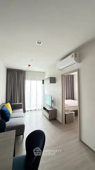 Modern apartment interior with living room and bedroom view, featuring sleek furniture and natural light.