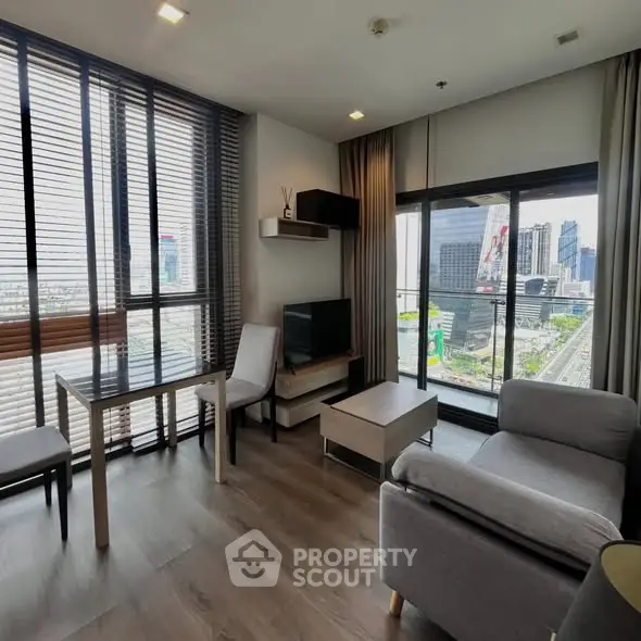 Modern living room with city view, featuring stylish furniture and large windows for natural light.