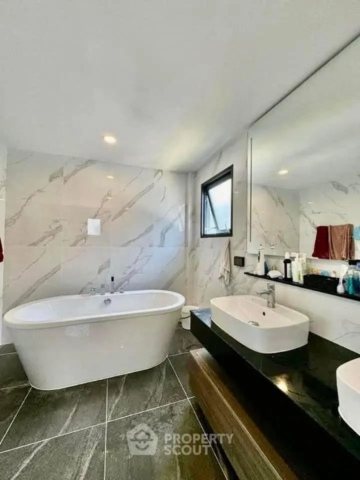 Luxurious bathroom with freestanding bathtub and modern vanity in elegant marble design.