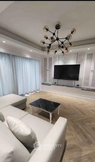 Luxurious living room with modern chandelier, marble accent wall, and sleek furniture.