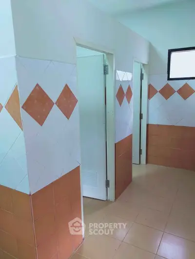 Spacious bathroom with tiled walls and multiple stalls, ideal for shared facilities.
