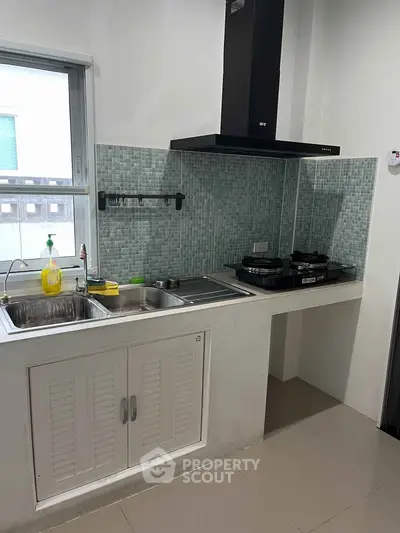 Modern kitchen with sleek cabinetry and gas stove, featuring a stylish backsplash and ample natural light.