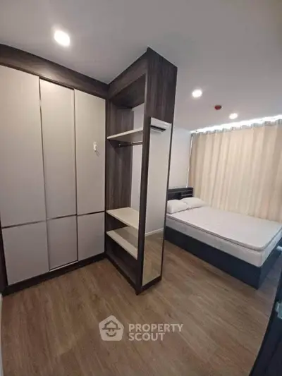 Modern bedroom with wooden flooring and built-in wardrobe, featuring a cozy bed and ambient lighting.