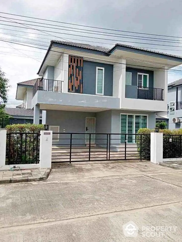 Modern two-story house with sleek design and gated entrance in suburban neighborhood.