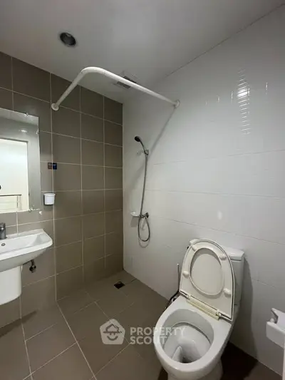 Modern bathroom with shower and toilet in a sleek, tiled design.