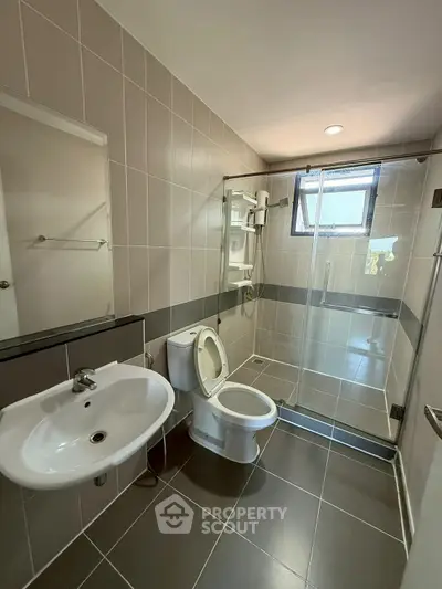 Modern bathroom with glass shower, sleek sink, and tiled walls in a contemporary home.