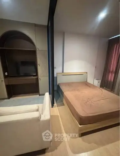 Modern studio apartment with cozy bed and built-in entertainment unit.