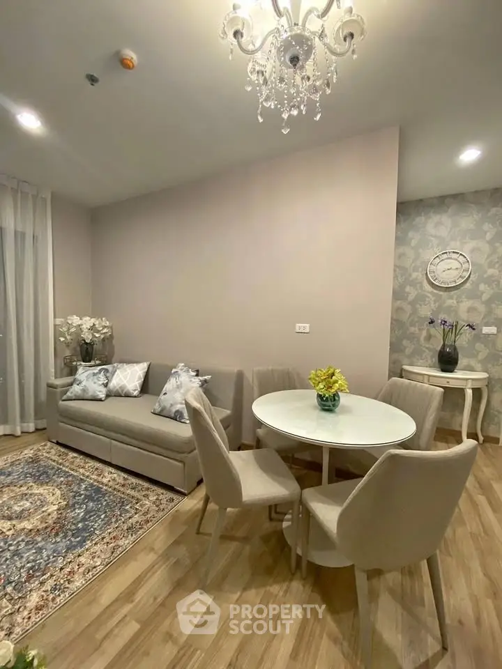 Elegant living room with chandelier, cozy sofa, and stylish dining set in modern apartment.
